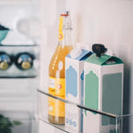 Nivona milk nozzle (NIML220) attached to a milk carton placed in the refrigerator next to a juice bottle