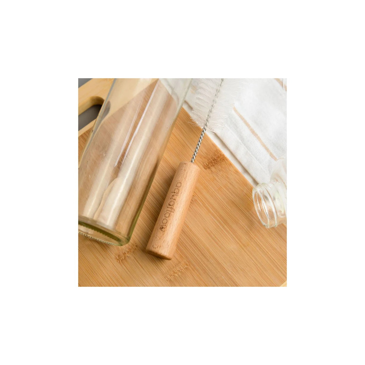 Aquafloow Bottle cleaning brush for carbonators — wooden handle with white‑fiber brush beside a glass bottle on