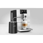 JURA Glacette cooler for glass milk container black (24167) next to a coffee machine, black cylindrical cooler with tube connected to